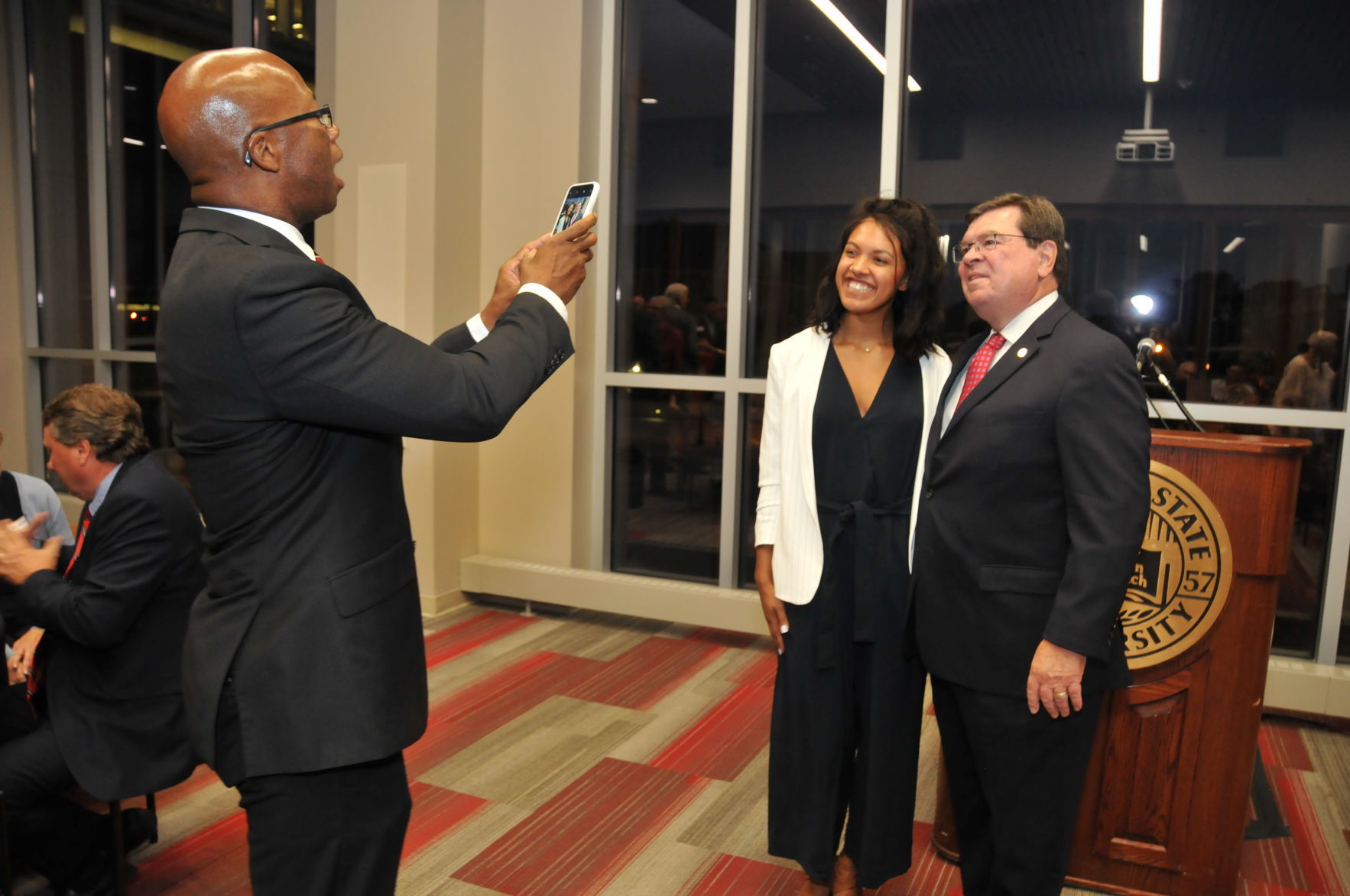 LJ Johnson taking a picture of Radiance Campbell, ISU President Larry Deitz
